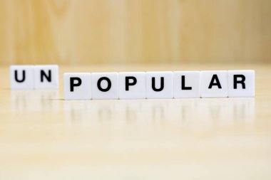  Popüler kelimesini oluşturan harfleri içeren bir sıra küçük beyaz plastik karo, popülerlikten popülerliğe dönüşüm kavramını temsil ediyor..