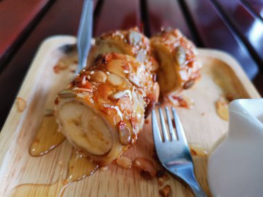 Muza sarılı krepler ve üzerine bal serpilmiş fındıklar.