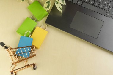 İnternet alışveriş konsepti. Küçük teslimat kutuları, akıllı telefon, alışveriş torbaları, dizüstü bilgisayardaki sepet standı. Boşluğu kopyala