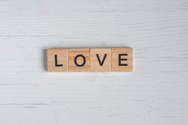 Aşk sözcüğünün üst görüntüsü eski beyaz ahşap arka plandaki kare ahşap fayanslardan serilmiştir. Sevgililer Günü kavramı.