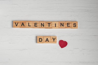 Sevgililer günü sözcüğünün üst görüntüsü kare ahşap fayanslardan ve eski beyaz ahşap arka planda kırmızı küçük kalplerden oluşuyordu..