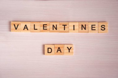 Sevgililer günü sözcüğünün üst görüntüsü pembe ahşap arka plandaki kare ahşap fayanslardan serili..