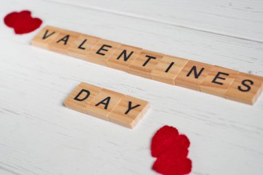 Kare tahta fayanslardan ve eski beyaz ahşap arka planda kırmızı küçük kalplerden sevgililer günü haberi yayıldı. Seçici odak.