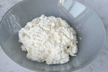 Gri beton arka planda gri bir tabakta süzme peyniri kapat. Kalsiyum ve protein kaynakları. Süt ürünleri, sağlıklı yiyecekler, diyet.