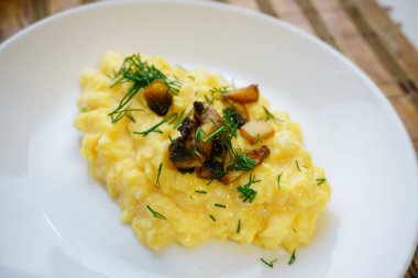 İştah açıcı, çırpılmış, mantarlı yumurta ve dereotlu beyaz tabakta. Sağlıklı protein kahvaltısı. Ev yemeği konsepti.