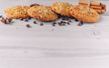 Kahve çekirdekleri, anason, tarçın çubukları ile süslenmiş taze pişmiş yulaf ezmesi kurabiyeleri, fotokopi alanı ile beyaz ahşap masa zemininde karanfiller. Menü düzeni için resim tasarımı. Lezzetli ve tatlı yemek konsepti.