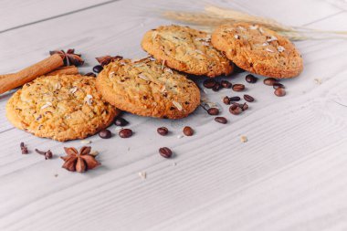 Kahve çekirdekleri, anason, tarçın çubukları, karanfil, buğday, ahşap arka planda yulaf gevreği ile süslenmiş taze pişmiş yulaf ezmesi kurabiyeleri. kopyalama alanı. Menü düzeni için resim tasarımı