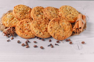 Kahve çekirdekleri, anason, tarçın çubukları, karanfiller ile süslenmiş yulaf ezmesi kurabiyelerinin beyaz ahşap masa arkasında kompozisyonu. kopyalama alanı. Menü düzeni için resim tasarımı.