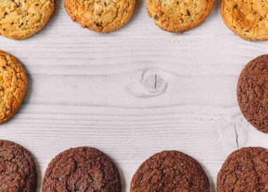 Gıda çerçevesi, beyaz ahşap arka planda yulaf ve çikolatalı kurabiyeler kopya alanı olan kare bir çerçeve şeklinde dizilmiştir. Ticari veya menü tasarımı için resim kullanımı. Lezzetli ve abur cubur kavramı