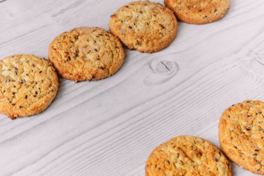 Beyaz ahşap masa zemininde çikolata parçacıklı ve yulaf ezmeli kurabiyelerden oluşan bir çerçeve. Ticari veya menü tasarımı için resim kullanımı. Kış, sonbahar, mutfak. Düz yatıyordu.