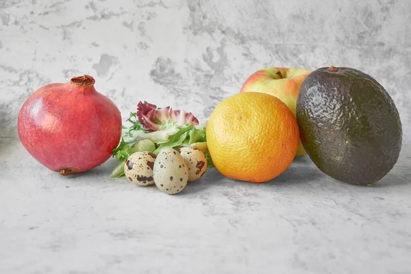 Yemek yapmak için gerekli malzemeler. Nar, bıldırcın yumurtası, marul yaprağı, mandalina, elma, gri beton arka planda avokado. Bağışıklığı güçlendirmek için vitamin almak için sağlıklı yiyecekler. Sağlıklı yaşam tarzı, yemek pişirme konsepti.