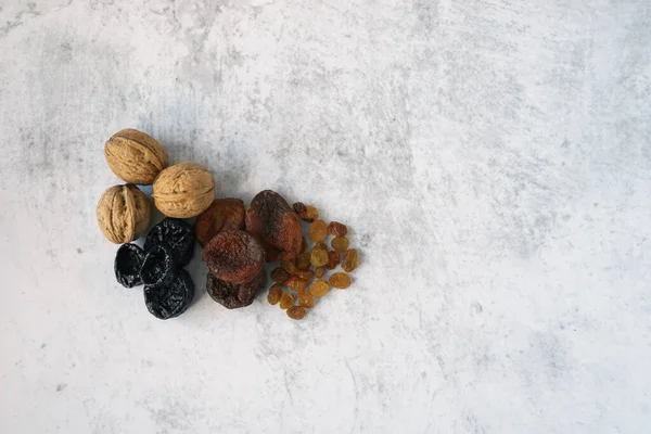 Kuru erik, ceviz, kuru kayısı, gri beton arka planda bir kompartımanda kuru üzüm. Sağlıklı bir yemek ve sağlıklı bir yaşam tarzı. Kış boyunca vitamin kaynağı olarak kurumuş meyveler.