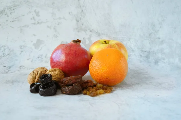 Aplle, portakal, nar, kuru erik, ceviz, kuru kayısı, gri beton arka planda kuru üzümler. Sağlıklı yemek ve sağlıklı yaşam tarzı. Kış boyunca vitamin kaynağı olarak meyveler.