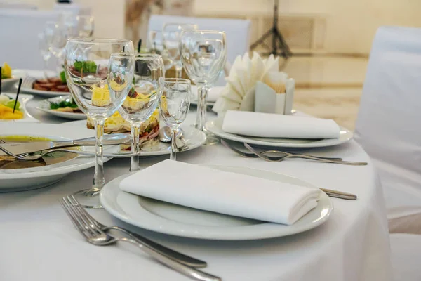 Masanın üzerinde açık renkli tabaklar ve beyaz masa örtüsü ile bir parti, düğün ya da diğer özel bir etkinlik için çeşitli yemekler var. Restoran işletme ve hizmet sektörü kavramı.