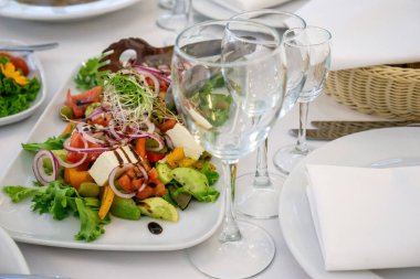 Masanın üzerinde açık renkli tabaklar ve beyaz masa örtüsü ile bir parti, düğün ya da diğer özel bir etkinlik için çeşitli yemekler var. Restoran işletme ve hizmet sektörü kavramı.