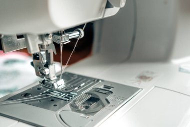 Dikiş makinesinin mekanizması çok yakın. Metin için kopyalama alanı olan beyaz dikiş makinesi iğnesi. Kumaş endüstrisi konsepti, teknoloji. Kumaş üretimi için fotoğraf.