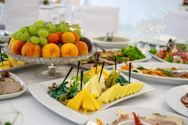 Masanın üzerinde açık renkli tabaklar ve beyaz masa örtüsü ile bir parti, düğün ya da diğer özel bir etkinlik için çeşitli yemekler var. Restoran işletme ve hizmet sektörü kavramı.