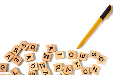 Sarı-siyah kalem ve kare tahta karoların üst görüntüsü İngiliz alfabesi beyaz bir zemine saçılmış ve yazı için boşluk bırakılmış. Düşünce geliştirme konsepti, dil bilgisi.