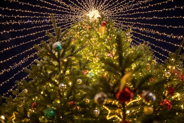 Kerstboom met decoratieve ballen, speelgoed en een glanzende slinger. zachte focus, achtergrond in vervaging. — Stockfoto