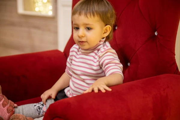 Pequeña linda niña sentada en una silla roja — Foto de Stock