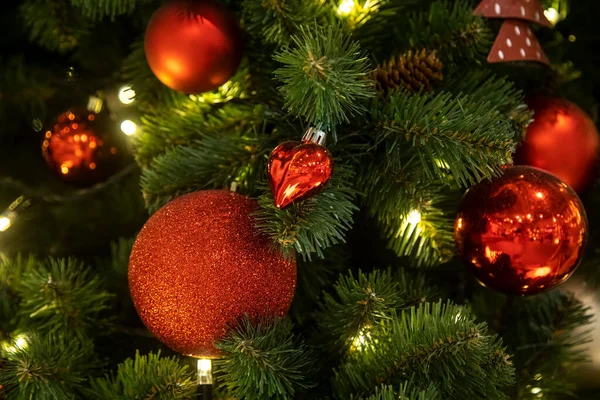 Een tak van een kerstboom versierd met rode ballen met speelgoed — Stockfoto