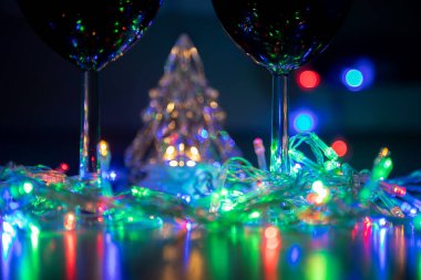 Çok renkli çelenklerle parlayan kristal ağaç ve siyah arka planda noel kutlaması.