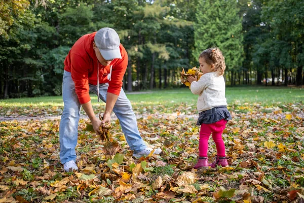 Маленькая девочка играет с отцом на свежем воздухе в осеннем парке — стоковое фото