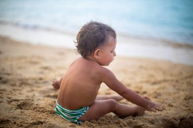 Sevimli çocuk deniz kenarında kumlarda oynuyor..
