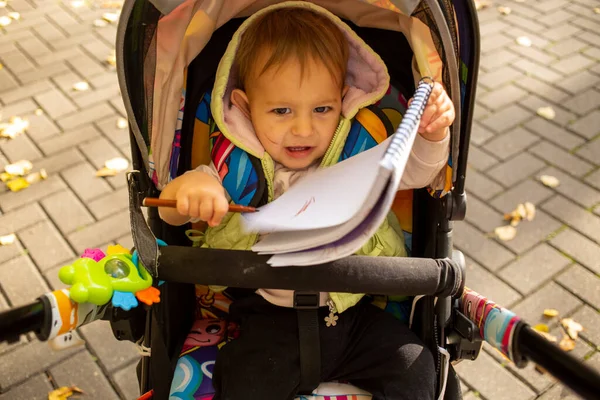 Lindo pequeño niño es travieso y sentado en un cochecito — Foto de Stock