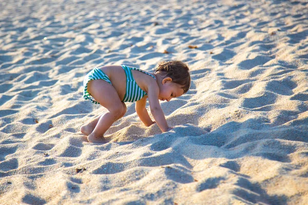 Mały cute maluch bawi się i wspiąć się na piasek plaży — Zdjęcie stockowe