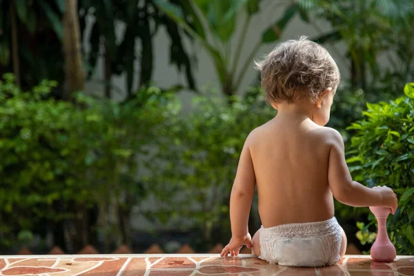 Чарівний малюк сидить на сходах будинку на сонячному світлі. вид ззаду . — стокове фото