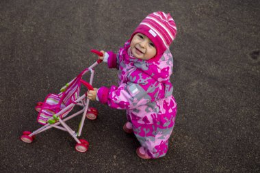 Ilık kış tulumu giymiş küçük çocuk oyun bahçesinde oynuyor. yumuşak odak