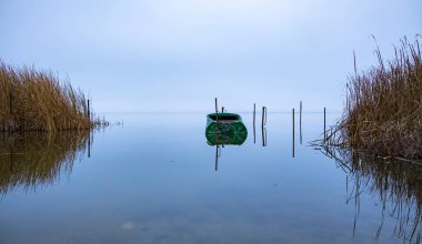 Gün doğmadan önce göle parketmiş boş bir tekne. Sabahın erken saatlerinde balık tutmak için. Kimse yok.
