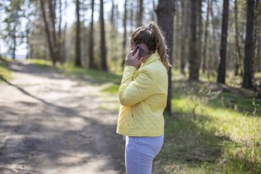 Kadın ormanda telefonda duygusal bir konuşma yapıyor. 5g hücresel iletişim konsepti