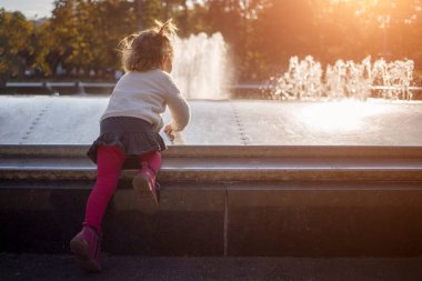 Sevimli küçük kız, güneşli bir günde parkta oynuyor. Kapat.