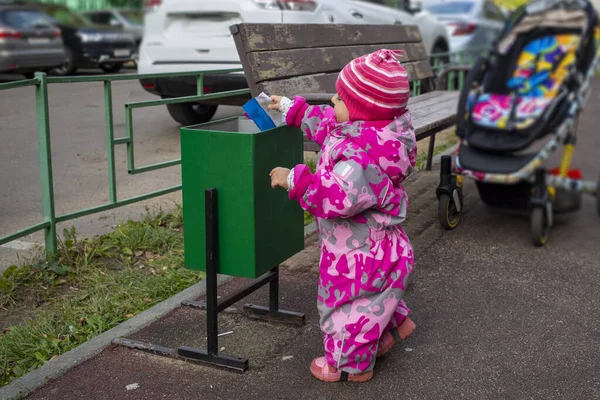 adorable toddler throws trash in a street bin