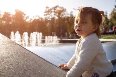 Sevimli küçük kız, güneşli bir günde parkta oynuyor. Kapat.