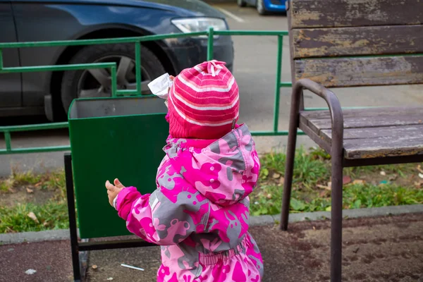 adorable toddler throws trash in a street bin