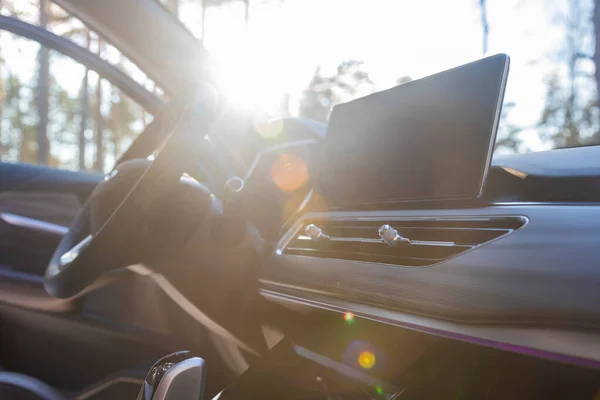 empty interior of a premium car in the sun.. multimedia monitor, interior ventilation deflectors, steering wheel. no people.