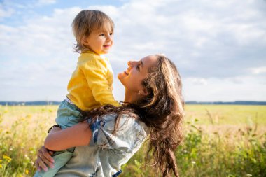 Mutlu anne ve bebek yazın güneşli bir günde tarlada oynuyorlar.