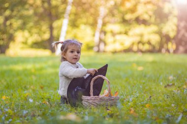 Toddler playing with witch hat in autumn sunny park.