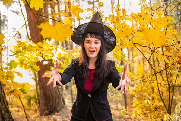 마법을 만드는 복장을 여자가 카메라에 나뭇잎을 던지며 웃는다 할로윈 — 스톡 사진