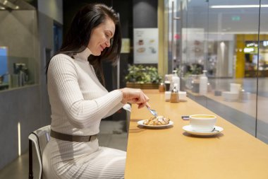 Kafkasyalı güzel, orta yaşlı bir kadının bir kafede kruvasan yerken portresi. Öğle yemeği molası