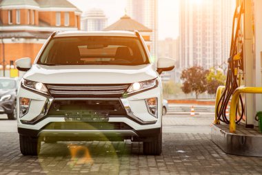 Benzin istasyonunda modern bir araba. Benzin döken beyaz bir SUV. Kapat.