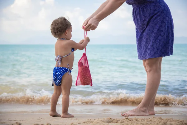 母親は子供に海のビーチでメッシュバッグを与える 幼い頃から生態文化は — ストック写真