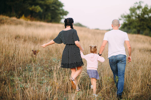 parents with their daughter walk the hills by the hand
