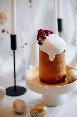 Paskalya sofrası. Beyaz paskalya yumurtaları, mumlar, dallar, beyaz kremayla süslenmiş kekler.