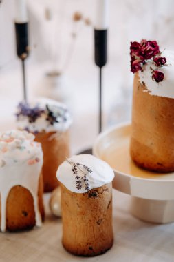 Paskalya sofrası. Beyaz paskalya yumurtaları, mumlar, dallar, beyaz kremayla süslenmiş kekler.