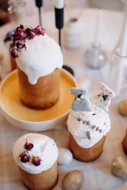 Paskalya sofrası. Beyaz paskalya yumurtaları, mumlar, dallar, beyaz kremayla süslenmiş kekler.