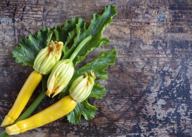 Büyük yeşil yapraklı altın kabak çiçekleri ve eski ahşap arka plan fotokopi alanı sağ tarafta. 